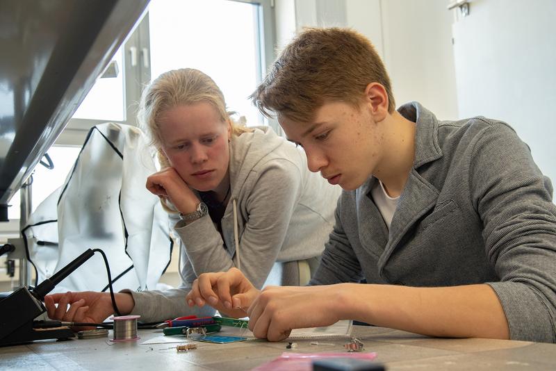 Karina Rother studiert Elektrotechnik im sechsten Semester. Sie betreut einen Besucher beim Löten von Bauteilen auf Leiterplatten und beim Herstellen seiner Taschenlampe