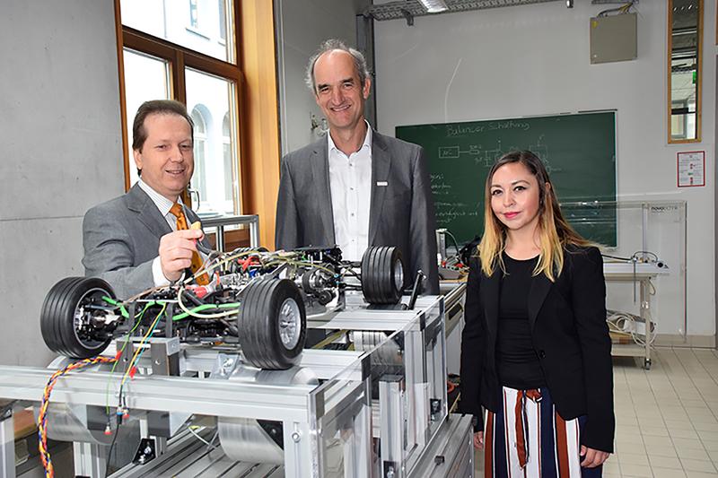 Prof. Dr. Siegfried Zürn (links im Bild) zeigt Rektor Prof. Dr. Christian Maercker und Liliana Zarco den Aufbau eines autonom fahrenden Modellautos. 