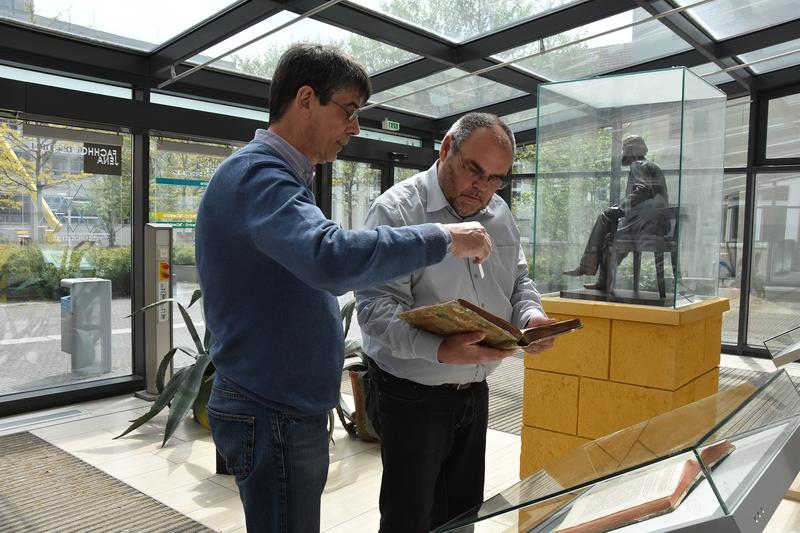 THULB-Werkstattleiter Frank Schieferdecker, li., und Rektor Steffen Teichert mit Newtons Original vor dem ausgestellten Faksimile. Re.die Skulptur von Ernst Abbe, Dauerleihgabe von ZEISS für die EAH 