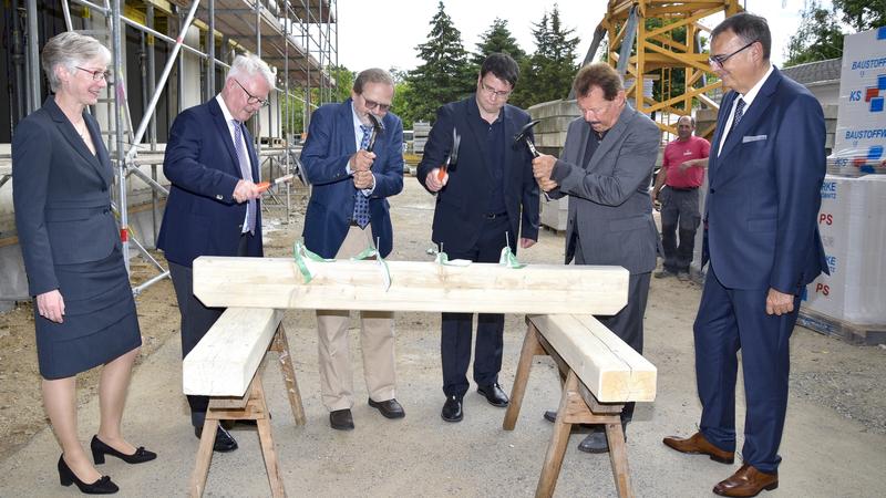 Beim Richtfest schwingen den Hammer (v.l.n.r.): Prof. Reichmann, Wilfried Winzer, Architekt Christian Strauss und Prof. Albrecht. Die künftigen Nutzer Prof. Schöck und Prof. Baretton schauen zu.