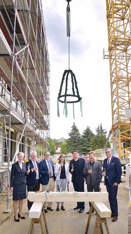 Unter der Richtkrone stoßen an (v.l.n.r.): Prof. Schröck, Dekan Prof. Reichmann, Wilfried Winzer, Gabriele Scharlipp vom Bauherrenteam, Architekt Christian Strauss, Prof. Albrecht und Prof. Baretton.