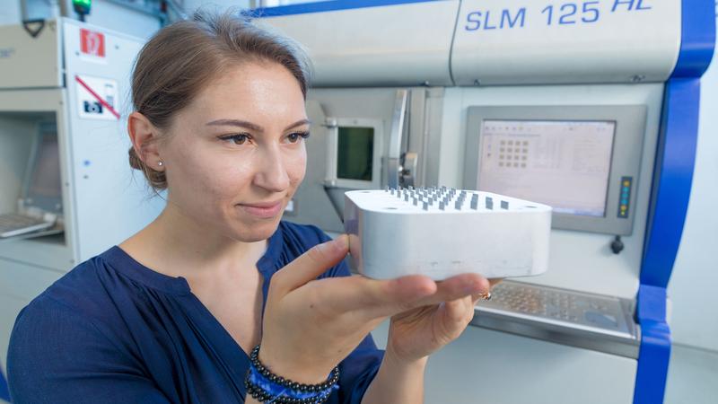 Ein im metallischen 3D-Druck gefertigter Hydraulikprüfkörper für die Luftfahrtanwendung samt Zugproben, an denen die Forscher die Zugfestigkeit und das Dehnverhalten des Materials untersuchen.