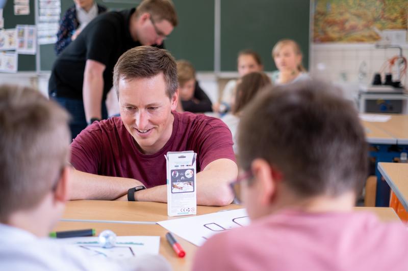 Informatik in der Grundschule: Die Kinder testen gemeinsam mit Prof. Dr. Gordon Fraser den Roboter auf ihrem Blatt Papier. 