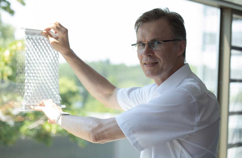 Professor Stefan Schäfer demonstriert am Prototypen, wie der innovative Sonnenschutz funktioniert. Durch Auseinanderziehen des Stoffs entstehen Öffnungen, die Licht durchlassen.