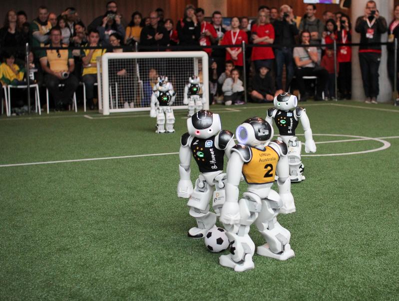 Two robots arrive at the ball and both try to gain possession. The photo was taken during the semifinal match against rUNSWift at RoboCup 2019 in Sydney.