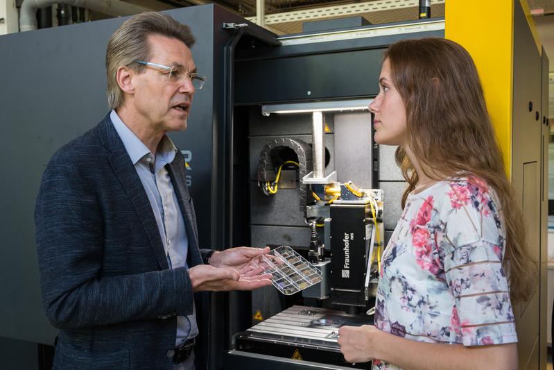 Professor Frank Mücklich erläutert der Masterstudentin Laura Ulrich die neue Laserinterferenz-Anlage.