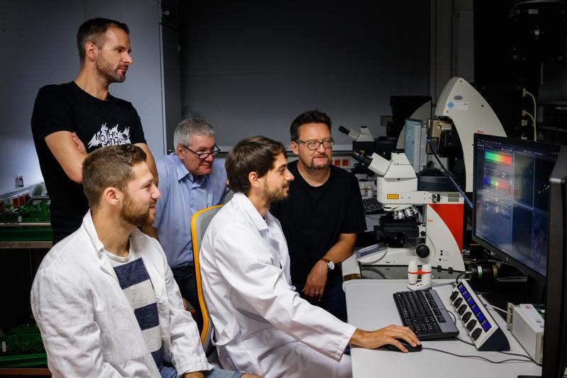 Daniel Lüdke zeigt seinen Kollegen die Ergebnisse der mikroskopischen Untersuchung.