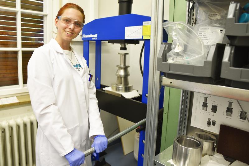 Tanja Manninger, Lehrstuhl für Mineralogie, erforscht Schnellzement mithilfe einer Presse, die das Wasser aus dem Zementstein hinausdrückt. (Bild: FAU/Luisa Macharowsky)