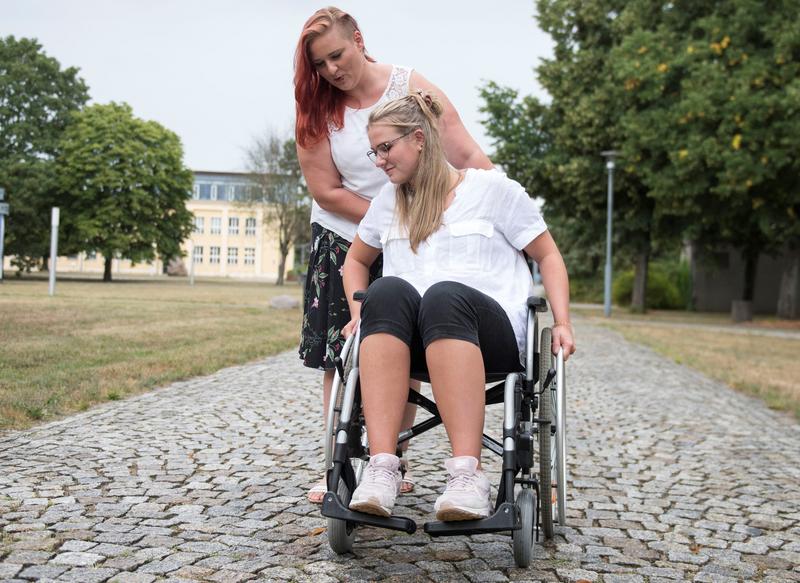 Die Studentinnen und Projektmitarbeiterinnen Lisa Barowsky (li) und Juliane Tackenberg prüfen die Möglichkeit, sich per Rollstuhl auf Kopfsteinpflaster fortzubewegen.