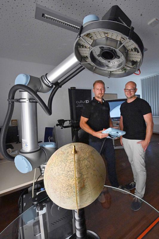 Dr. André Karliczek (l.) und Dr. Andreas Christoph nehmen an der Thüringer Universitäts- und Landesbibliothek Jena einen 3D-Scanner zur digitalen Erfassung von Sammlungsobjekten in Betrieb.