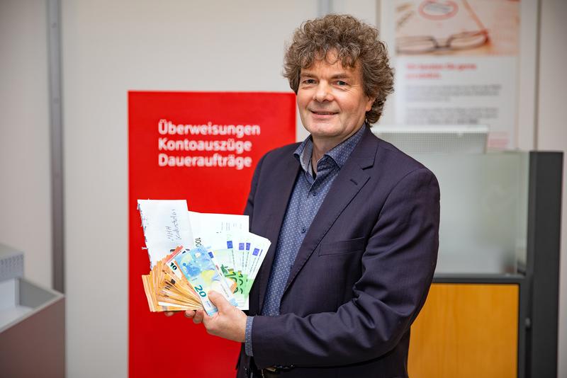 Dr. Eckhard Schenke, Leiter der Stabsstelle Fundraising, der die 4.500 Euro Bargeld einzahlt.