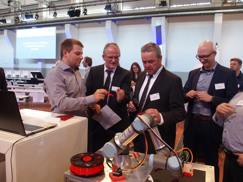 Forschung zum Anfassen: Am Stand der Hochschule Aalen demonstrierte Matthias Eberhard (links) vor Vertretern des BMBF und des Projektträgers die Funktionsweise des neuen 3D-Druckers. 