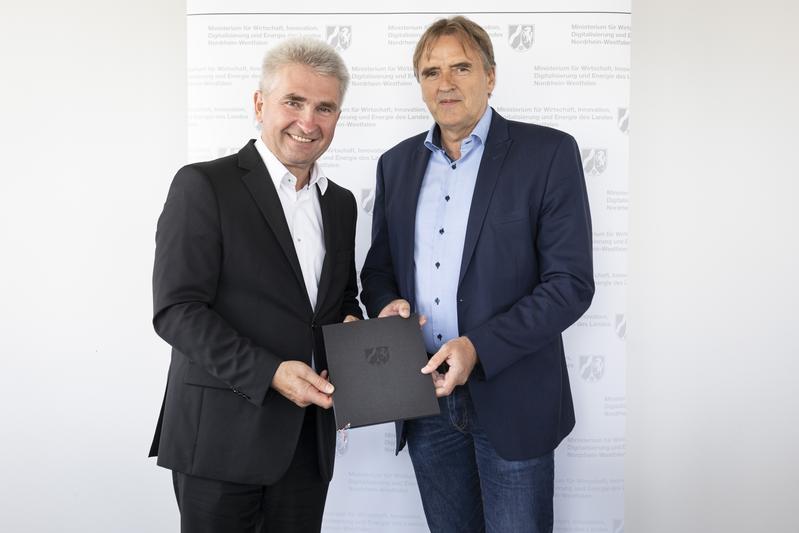 NRW-Digitalminister Prof. Dr. Andreas Pinkwart (l.) überreichte einen der Förderbescheide für die „Blockchain-Reallabore“ persönlich an Prof. Norbert Pohlmann (r.).