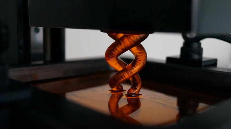 3D-Druck einer schichtweise entstehenden Doppelhelix aus flüssigem Acrylharz, die mittels Belichtung an einer Bauplattform aushärtet. Foto: Anne Asmacher, Freiburger Materialforschungszentrum. 