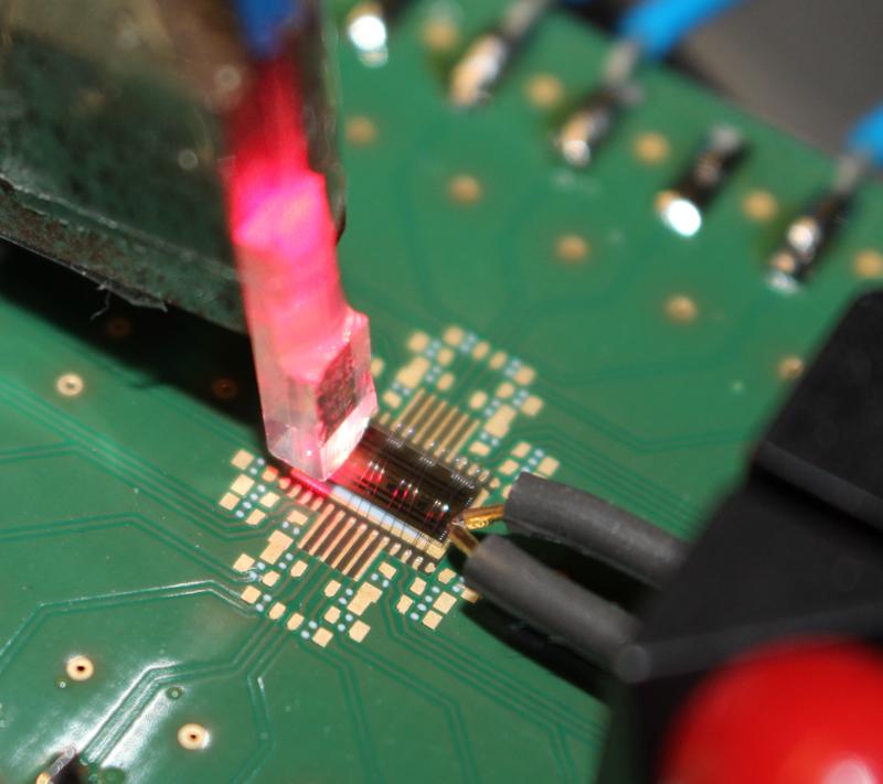 Electronic-optical silicon chip with coupling of optical (left) and high-frequency electrical signals (right) on a conventional electrical circuit board.