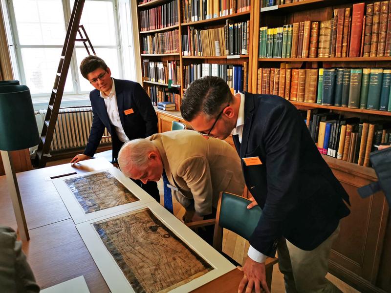 Philipp Köhner (links) und Thomas Wittmann (rechts) vom Lehrstuhl für Alte Geschichte begutachten zusammen mit Prof. Dr. Richard Talbert (Chapel Hill, USA) Teile der Tabula Peutingeriana im Original.