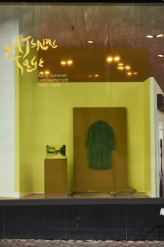 Darmstädter Läden zeigen Exponate, mit Bezug auf Arno Schmidt und seine Zeit. Henschel Darmstadt zeigt einen Mantel von Schmidts Frau Alice, den sie 1956 in der Darmstädter Innenstadt gekauft hatte.