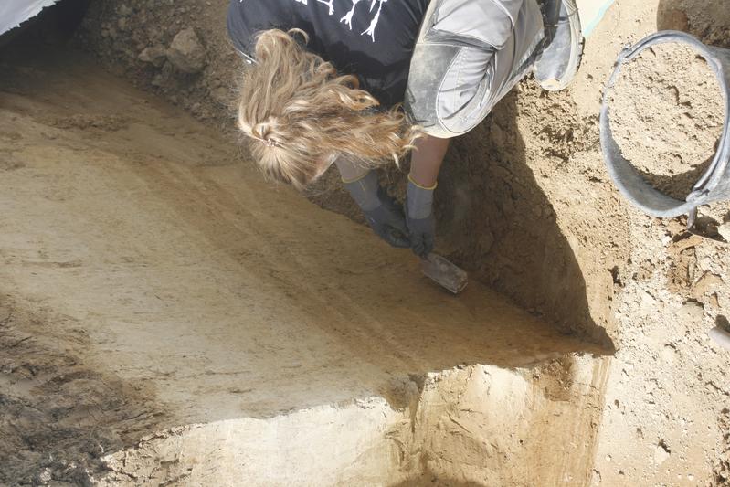 Gina Lang, Studentin der Ur- und Frühgeschichte an der Universität Rostock  präpariert das geologische Profil, um die Fundschichten sichtbar zu machen 