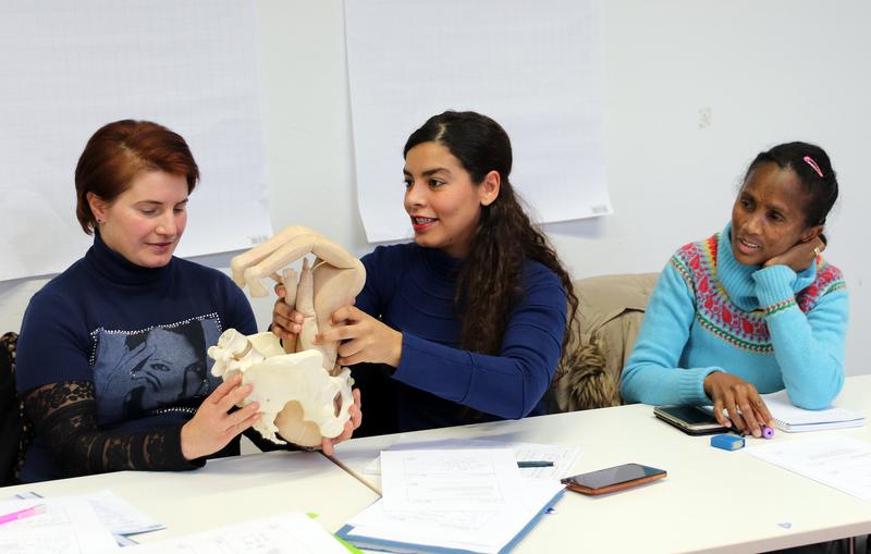 Teilnehmerinnen des Anpassungslehrgangs für Hebammen an der Evangelischen Hochschule Berlin üben die Geburt am Modell. 