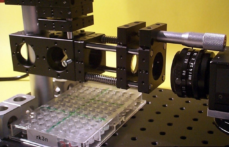 © Fraunhofer IFF - Ein neues optisches Verfahren kontrolliert Füllstände auf Mikrotiterplatten: Die Kamera rechts zeichnet einen an der Flüssigkeitsoberfläche reflektierten und fokussierten Lichtstrahl auf und ermittelt so deren Höhe.
