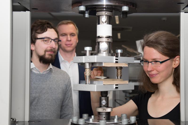 Nachwuchsgruppenleiter Florian Wallburg, Professor Stephan Schönfelder und Doktorandin Ulrike Käppeler (v.l.n.r.) an einer Prägemaschine im Werkstofflabor der HTWK Leipzig.