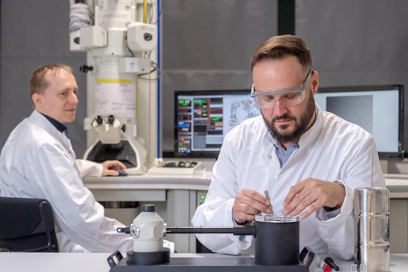 Die Erstautoren, Dr. Christoph Kaiser, beim Transfer eines Kryo-Proteinpräparates in einen, mit flüssigem Stickstoff gekühlten Probenhalter und Dr. Carsten Peters am Transmissionselektronenmikroskop.