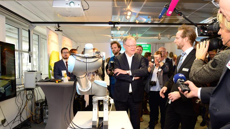 Ministerpräsident Stephan Weil lässt sich von Martin Günther erläutern, wie Menschen und Roboter als hybrides Team Fertigungsaufgaben gemeinsam bewältigen. Foto: Universität Osnabrück/Elena Scholz