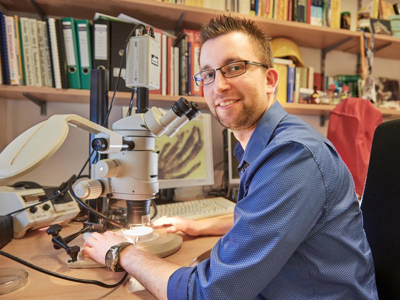 Jonas Barthel vom Institut für Geowissenschaften der Universität Bonn am Mikroskop. 