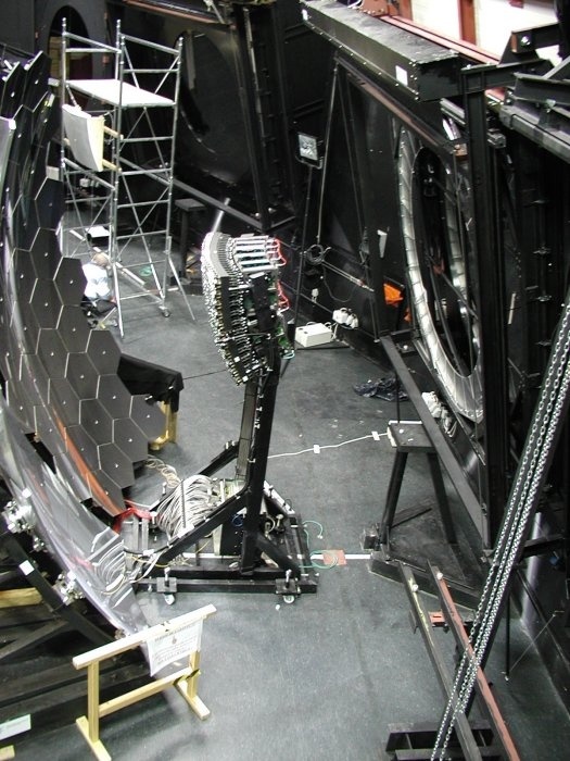 Innenansicht des Teleskopgebäudes mit Fluoreszenzdetektor. Zu erkennen sind die Teleskopöffnung mit Korrekturlinse (rechts), Photomultiplier-Kamera (Mitte), und das 11 m2 große Spiegelsystem (links).