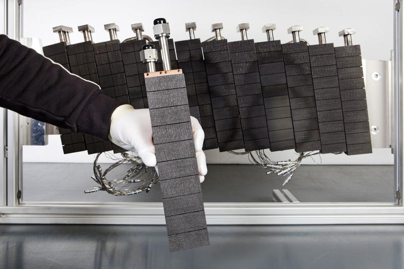 •	One of the 890 divertor elements. In the background: the prototype of a divertor plate assembled from these elements after a heat test in IPP’s GLADIS test rig. The stress marks are clearly 