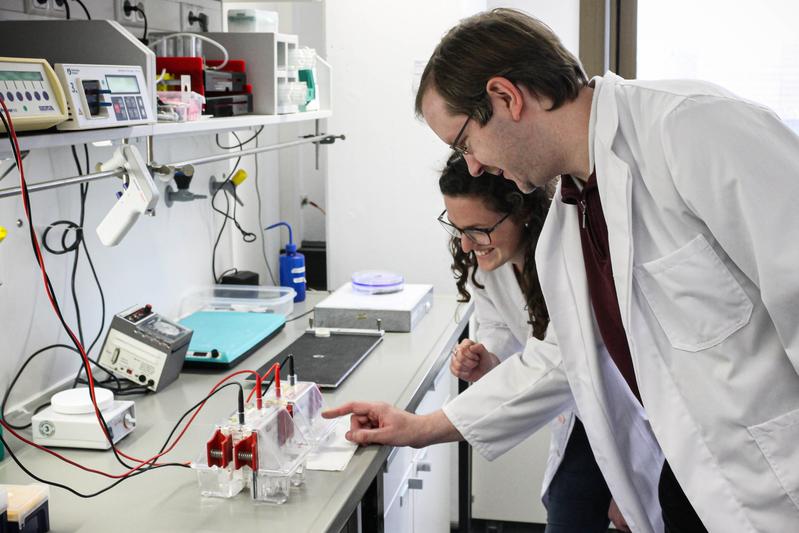 Clarissa Lanzloth B.Sc. und Dr. Frank Mickoleit in einem Labor der Bayreuther Mikrobiologie. Die Elektrophorese-Apparatur dient der Auftrennung und Analyse von Proteinen.