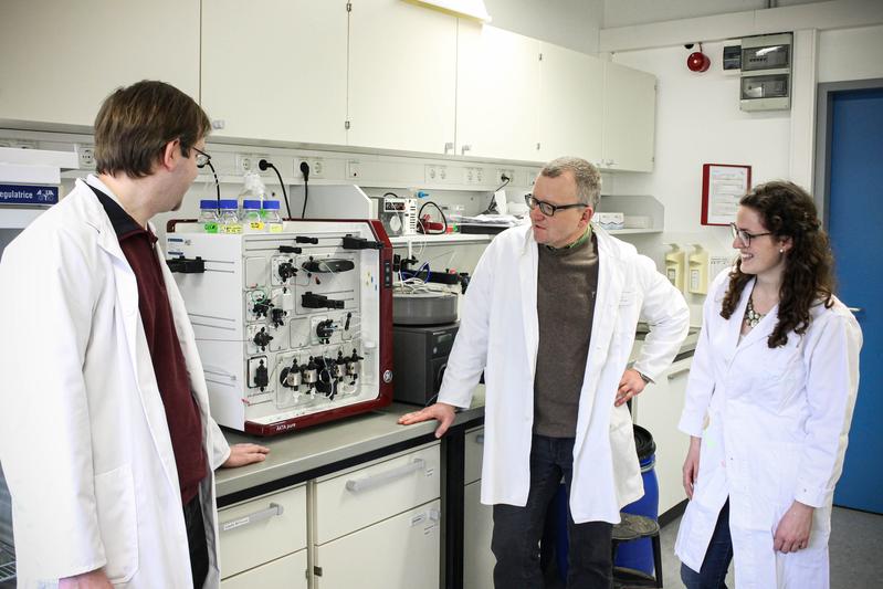 Dr. Frank Mickoleit, Prof. Dr. Dirk Schüler und Clarissa Lanzloth B.Sc. an einem Gerät zur Analyse, Isolation und Reinigung von Proteinen. 