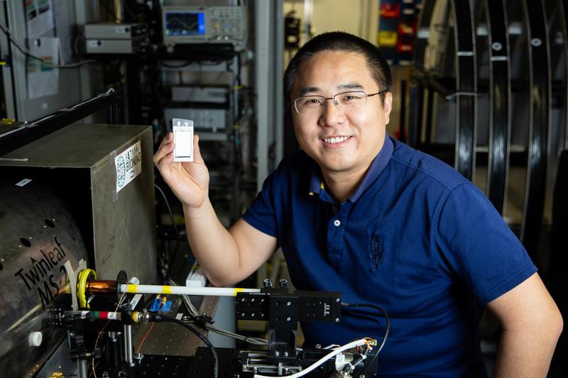 Yinan Hu, a member of Professor Dmitry Budker's research group at JGU, holding a battery cell, alongside a device which measures the state of charge