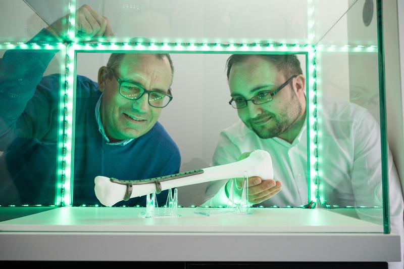 Professor Stefan Diebels (l.) und DFKI-Forscher Christian Wolff mit einem maßgefertigten Implantat für einen Unterschenkelbruch.