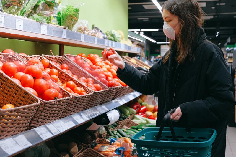 Frau mit Gesichtsmaske: Einkaufen im Supermarkt in Zeiten der Corona-Pandemie. 
