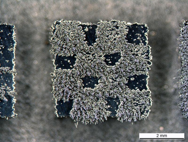 Eisenspäne haften auf diesem Mini-Schachbrett mit vier Millimetern Kantenlänge. Die teils magnetische Struktur wurde aus einer einzigen Sorte Stahlpulver bei verschiedenen Temperaturen produziert.