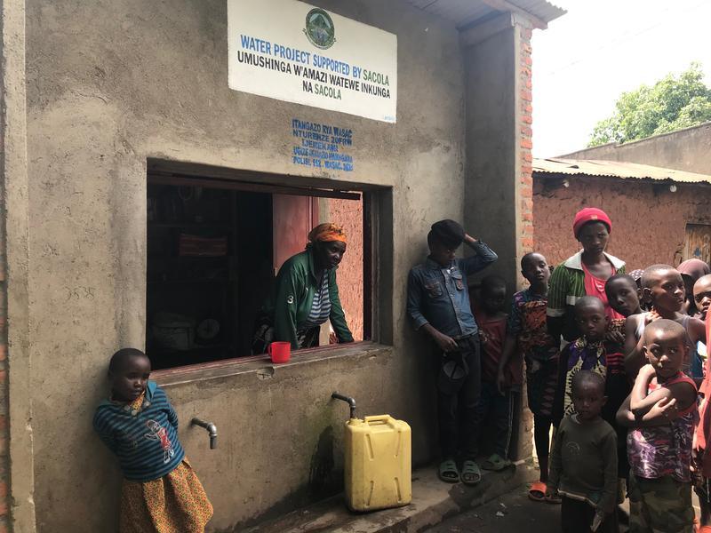 In Rwanda, a woman collects payments for water. The money is reinvested in the community. 