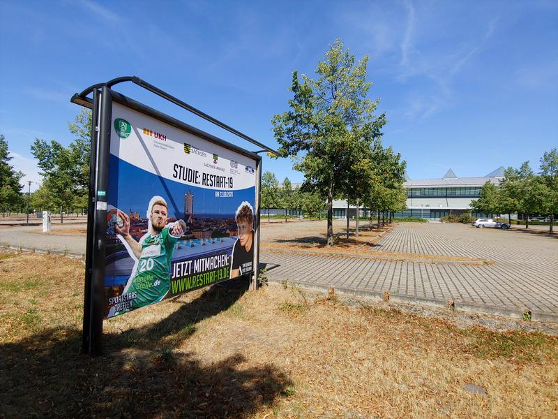Vor der Arena Leipzig weist ein Schild auf das Experiment im Rahmen des Projektes RESTART-19 hin
