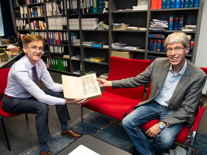 Mit dem Werk des Rechtsgelehrten Azo Portius: Prof. Dr. Martin Schermaier (links) und Bibliothekar Carl Erich Kesper (rechts) im Institut für Römisches Recht und Vergleichende Rechtsgeschichte der Universität Bonn. 