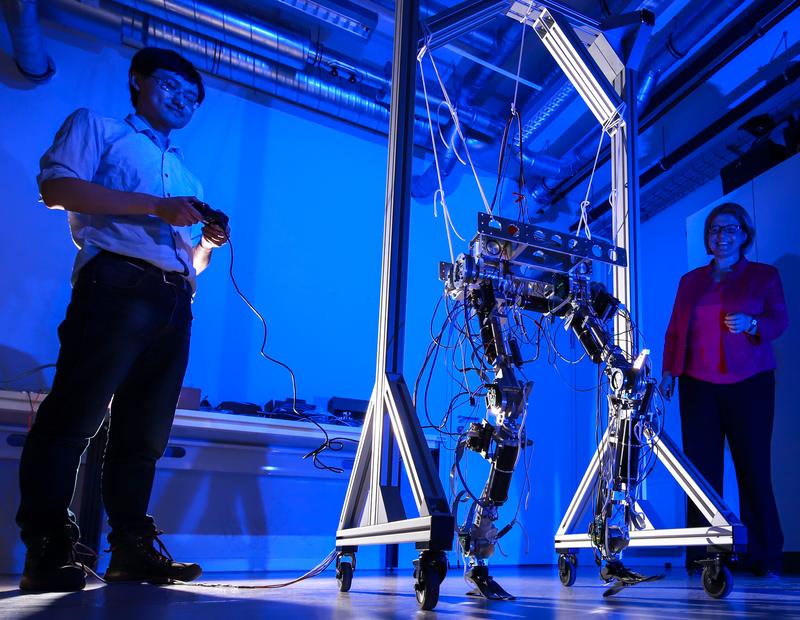 Doktorand Hongxi Zhu und Professorin Ulrike Thomas probieren gemeinsam den Laufroboter aus, in dem das nachgiebige Robotergelenk integriert werden kann.