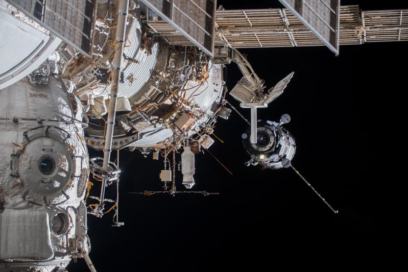 Eine Sojus-Kapsel nähert sich der ISS, im Vordergrund ist die stabförmige Icarus-Antenne zu sehen. 