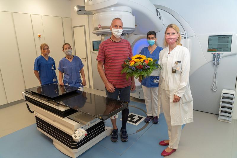 Dr. Christina Jentsch von der Klinik für Strahlentherapie und Radioonkologie (rechts) begrüßt den ersten mit dem neuen Linearbeschleuniger (LINAC) behandelten Patienten Jens Ulrich mit einem Blumenstrauß. 