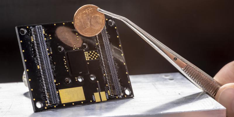 The prototype of the particle sensor (black square in the middle of the board) developed atTU Graz compared in size with a one-cent coin.