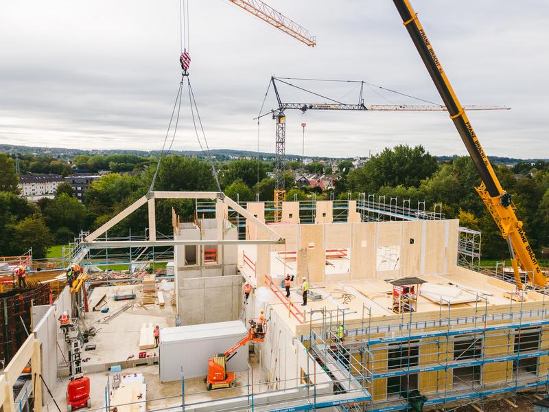  20200908_276_UWH_Baustelle_Videodreh_Sprengwerk_DJI__c_JohannesBuldmann_0179.jpg Positionierung eines Fachwerkträgers: Nach nur rd. neun Wochen werden die umfangreichen Holzarbeiten an dem Holzhybrid-Neubau abgeschlossen sein.