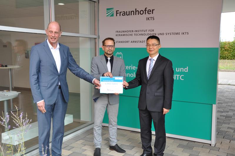 Thuringia's Minister of Economics and Science Wolfgang Tiefensee (left) symbolically hands over the grants to Dr. Roland Weidl, head of BITC, and Jason Chen, CATT site manager.