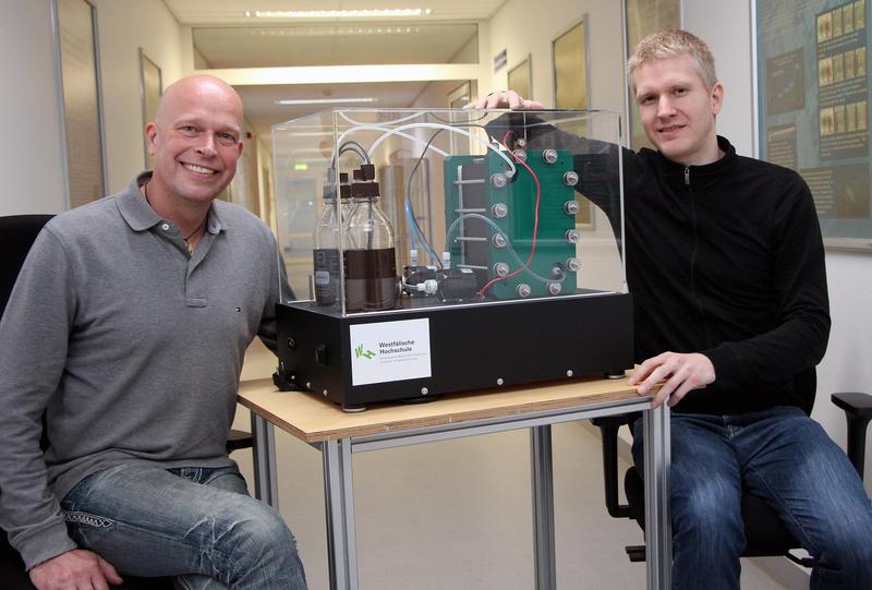 Prof. Dr. Michael Schlüter (l.) und Stefan Palte arbeiten an Konzepten für den Einsatz von Vanadium-Redox-Fluss-Batterien als stationäre Energiespeicher in Kläranlagen. Im Bild: ein Modell der Batterie.