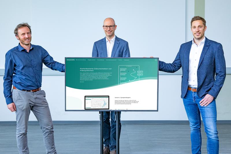 Jens Wille (Geschäftsführer Ubilabs), Dr. Gernot Beutel (Projektleitung) und Dennis Medefind (Projektmanagement MHH) (v.l.) mit einer schematischen Darstellung der Funktionsweise von KADOIN.