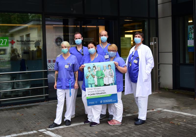 Das Team der Notaufnahme des Zentrums für Innere Medizin am Dresdner Uniklinikum präsentieren das Plakat der VUD-Kampagne. Darunter sind Franziska Angermann, Pflegerische Leiterin (3. V.l.) und Dr. von Bonin, ärztliche Leiterin der Noztaufnahme.