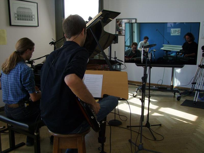 Studierende der Musikhochschulen in München und Hannover musizieren für das Projekt „LIPS“ gemeinsam im digtalen Raum – beinahe ohne spürbarer Verzögerung. Auf dem Bild HMTM-Studierenden in München vor Ort, die HMTMH-Studierenden auf dem Monitor.
