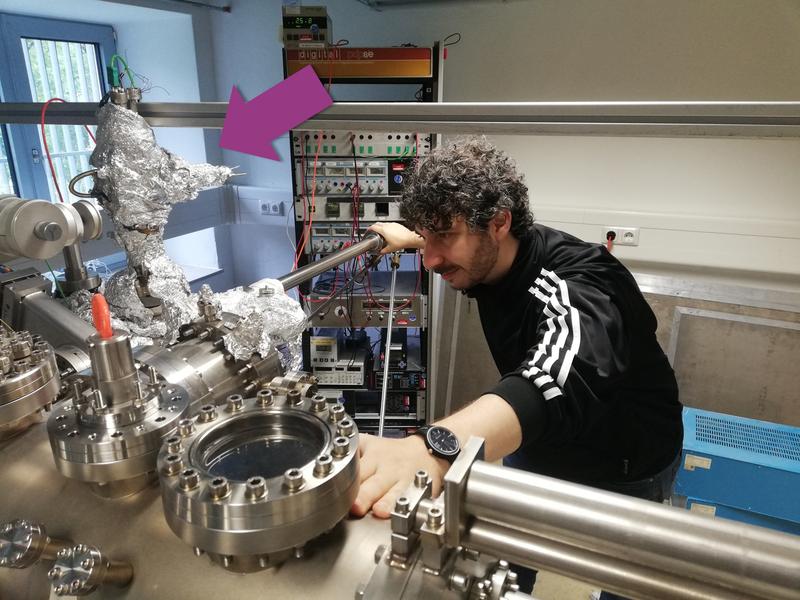 Dr. Gianluca Galeotti an der Ultra-Hoch-Vakuum Anlage in der die Kohlenstoff-gebundenen Nanostrukturen mit der RAQ (Pfeil) gewachsen und mit dem Rastertunnelmikroskop untersucht wurden.